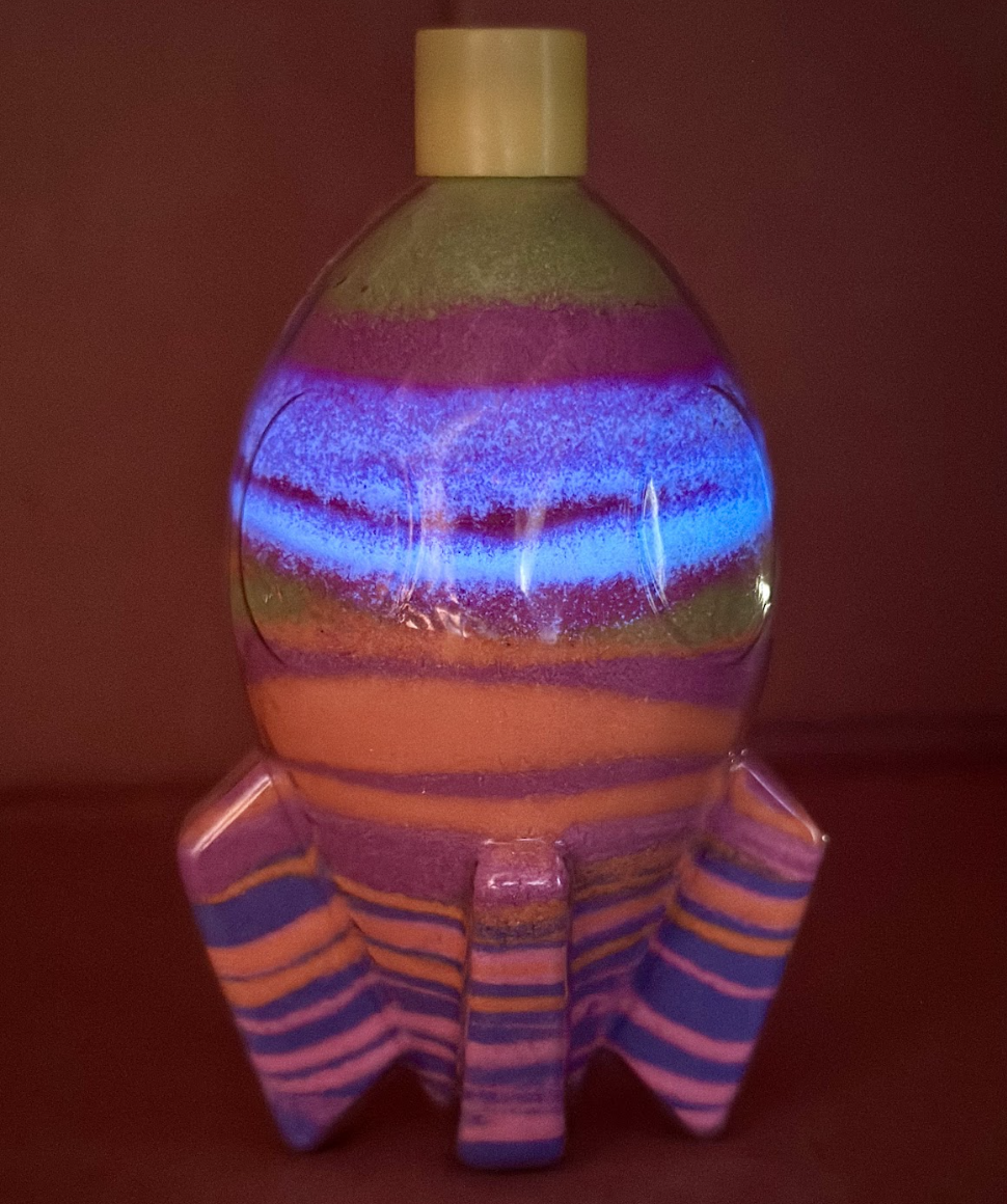 A completed glowing sand art shield bottle.